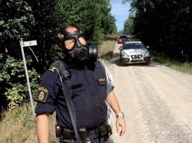  En polisman med en gasmask vid avspärrningarna vid Möljneryd utanför Ronneby, där ett Jas Gripen-flygplan kraschade under förmiddagen.