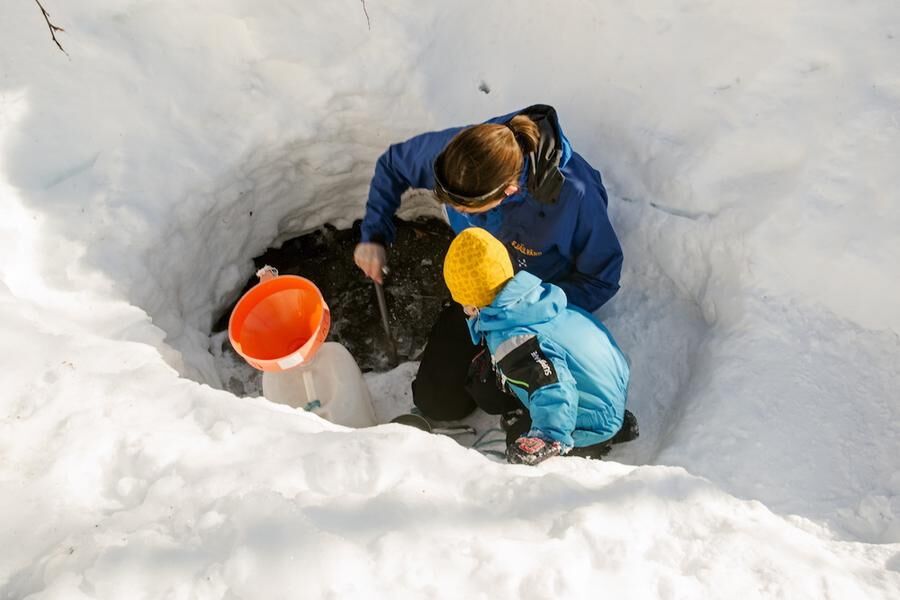 Vattenhämtning. Från en öppen källa i snön fyller mamma Annika och sonen John vattendunkarna.
